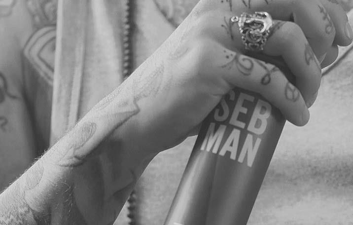A tattoed hand holds a can of Seb Man hairspray