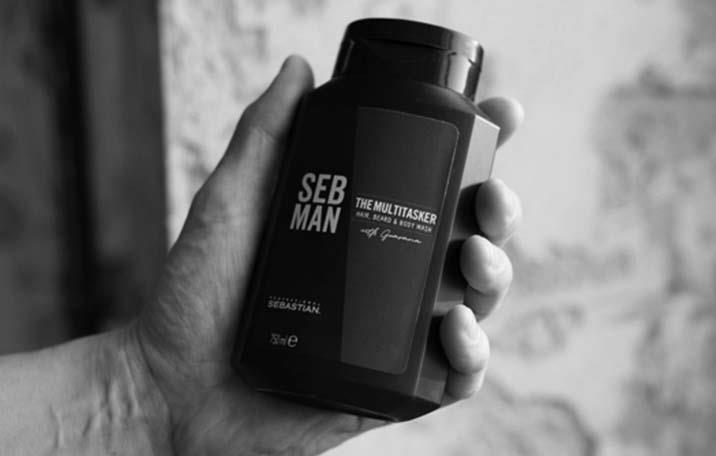 A bottle of The Multi-Tasker beard, hair and body wash held in a hand