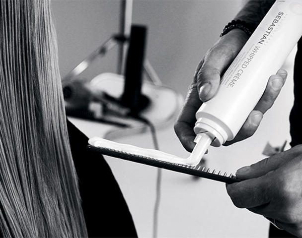 Person squirting styling cream onto a comb
